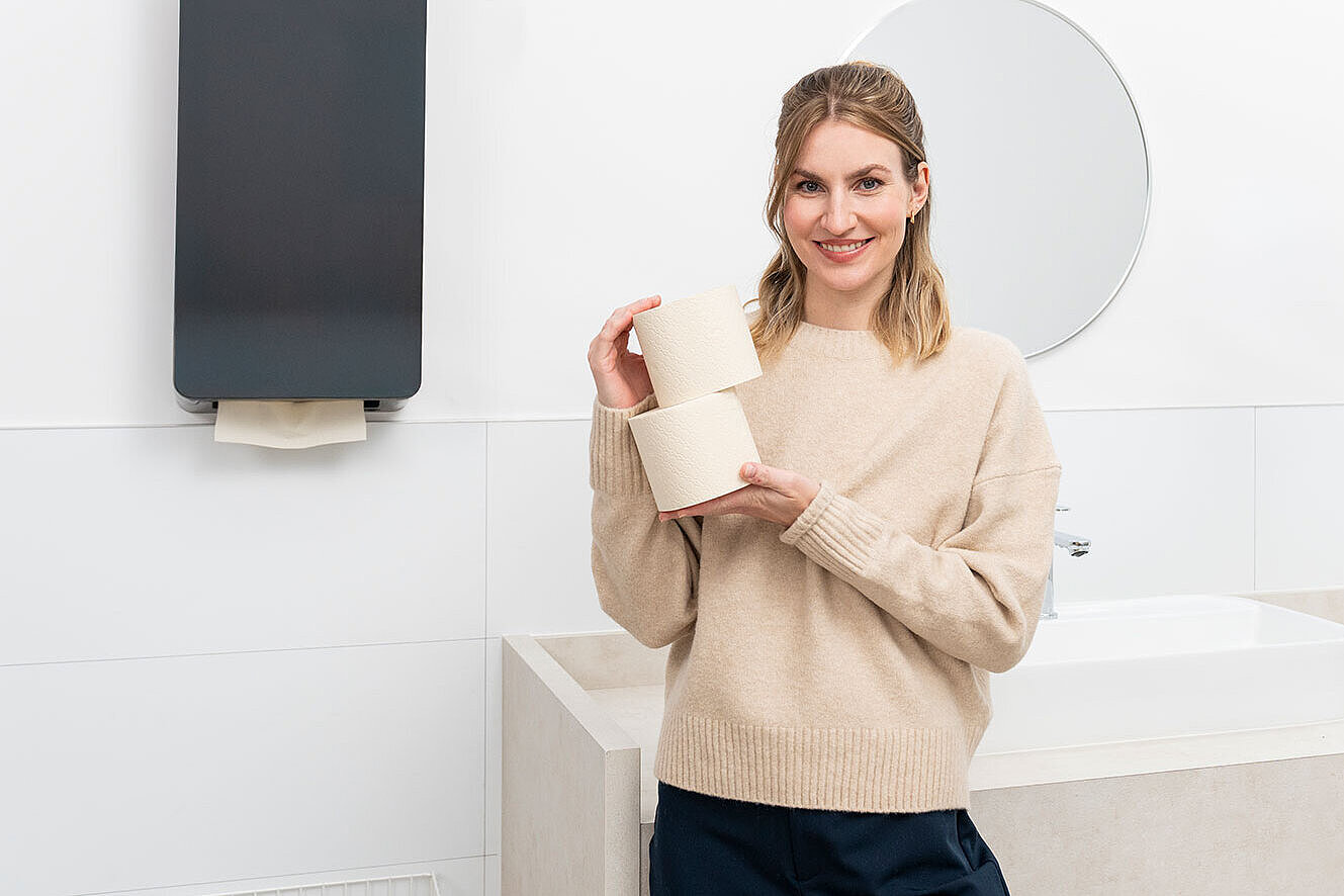 Frau zeigt auf ein digitales Display an einer Wand in einem modernen Innenraum.