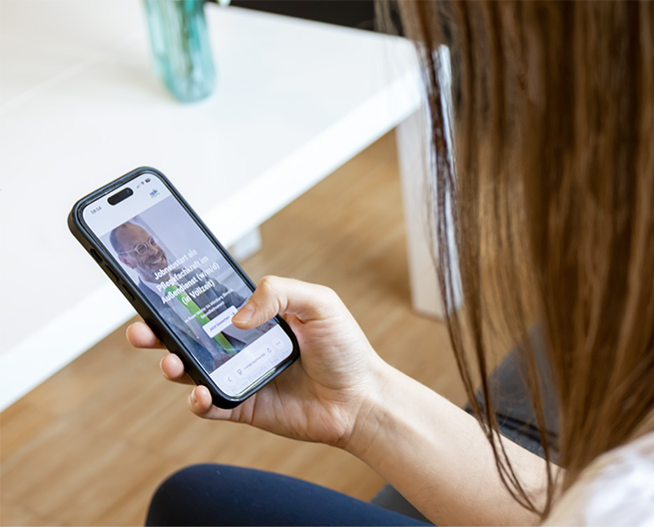 Frau schaut auf Handy in ihrer Hand, dort ist die Website für Schnellbewerbungen geöffnet.
