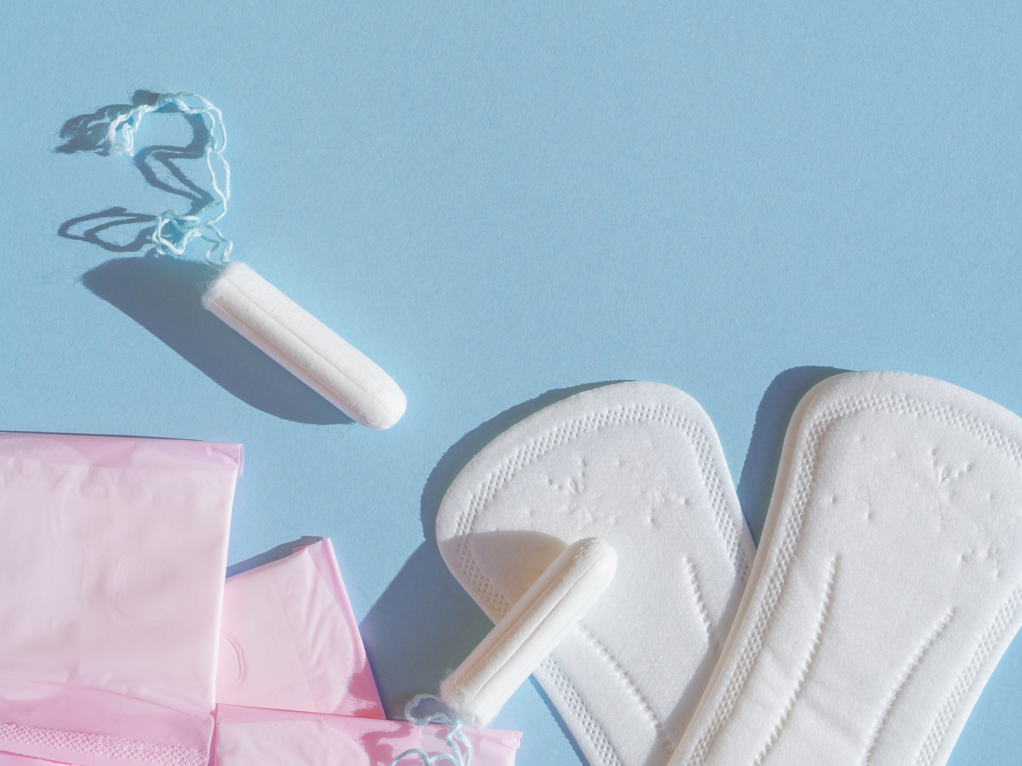 Tampon, eingepackte Damenbinden und Slipeinlagen auf farbigem Hintergrund.