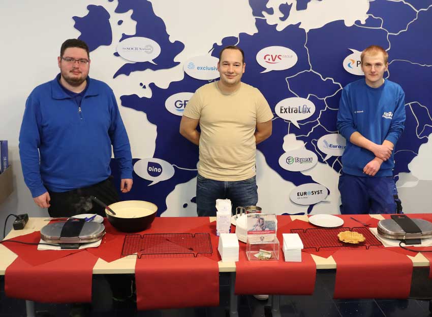 Azubis stehen vor Tisch und backen Waffeln