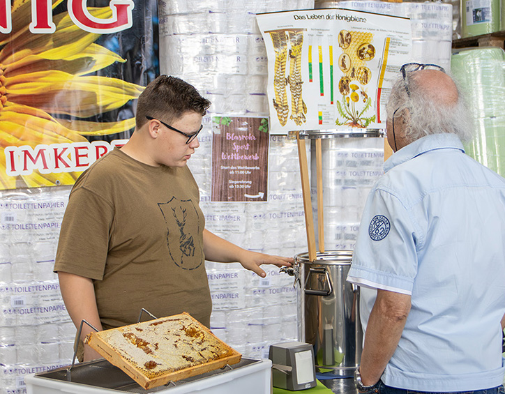 Besucher informieren sich am Bienenstand über Honig und Imkerei beim KLEIN Sommerfest 2026 in Wilnsdorf mit Einblicken in die Produktion.