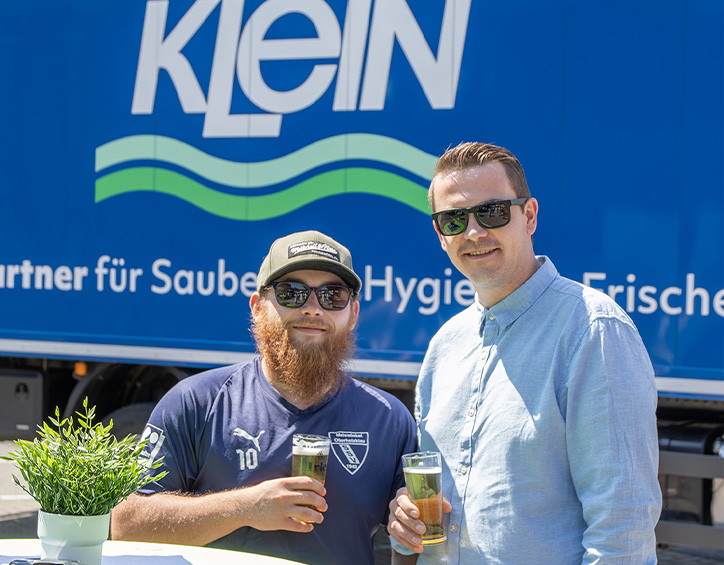 Zwei Teilnehmende stehen mit Getränken vor einem KLEIN LKW beim Sommerfest 2026 auf dem Firmengelände in Wilnsdorf.