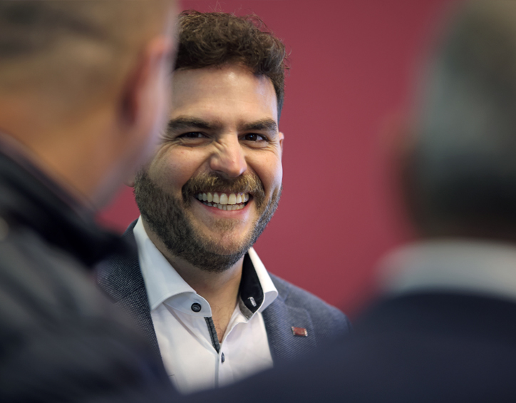 Person in Businesskleidung im Gespräch auf der CMS Berlin, vor rotem Hintergrund mit Messebranding.
