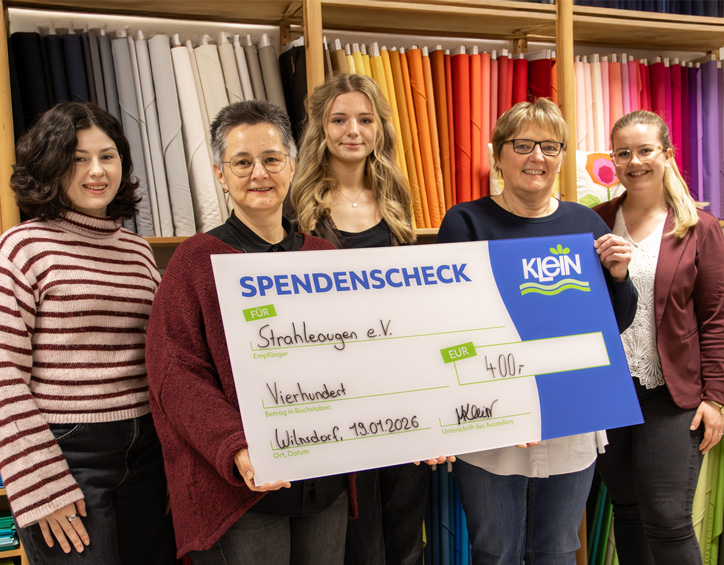Fünf Personen stehen zusammen und präsentieren einen großen Spendenscheck über 400 Euro zugunsten des Vereins Strahleaugen e. V.
