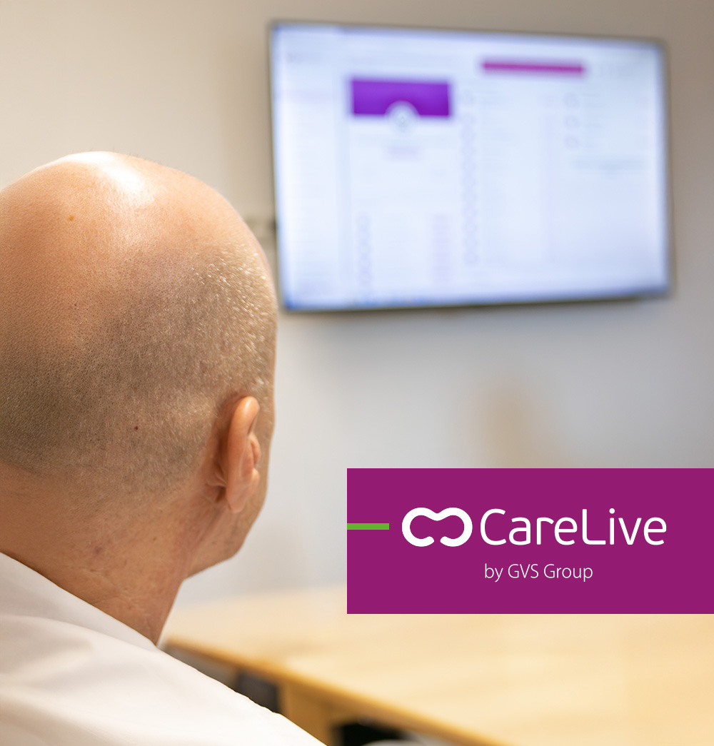 Eine Person blickt auf einen Bildschirm, auf dem die CareLive Plattform mit übersichtlicher Benutzeroberfläche angezeigt wird. Im Vordergrund ist das CareLive Logo zu sehen.